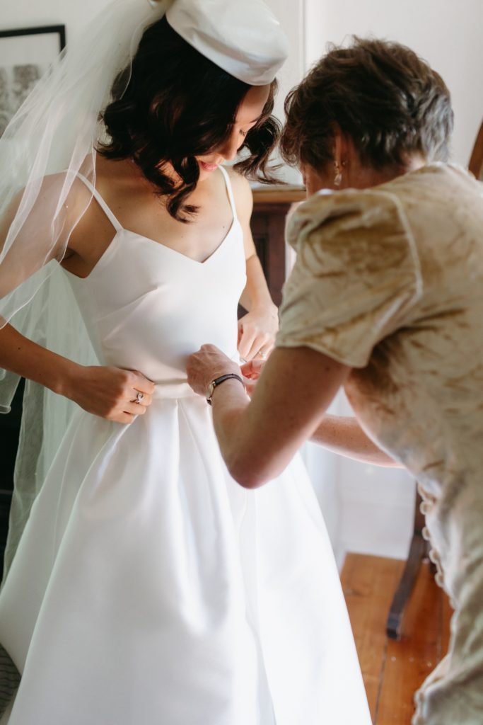 Mother helping daughter get into her wedding dress